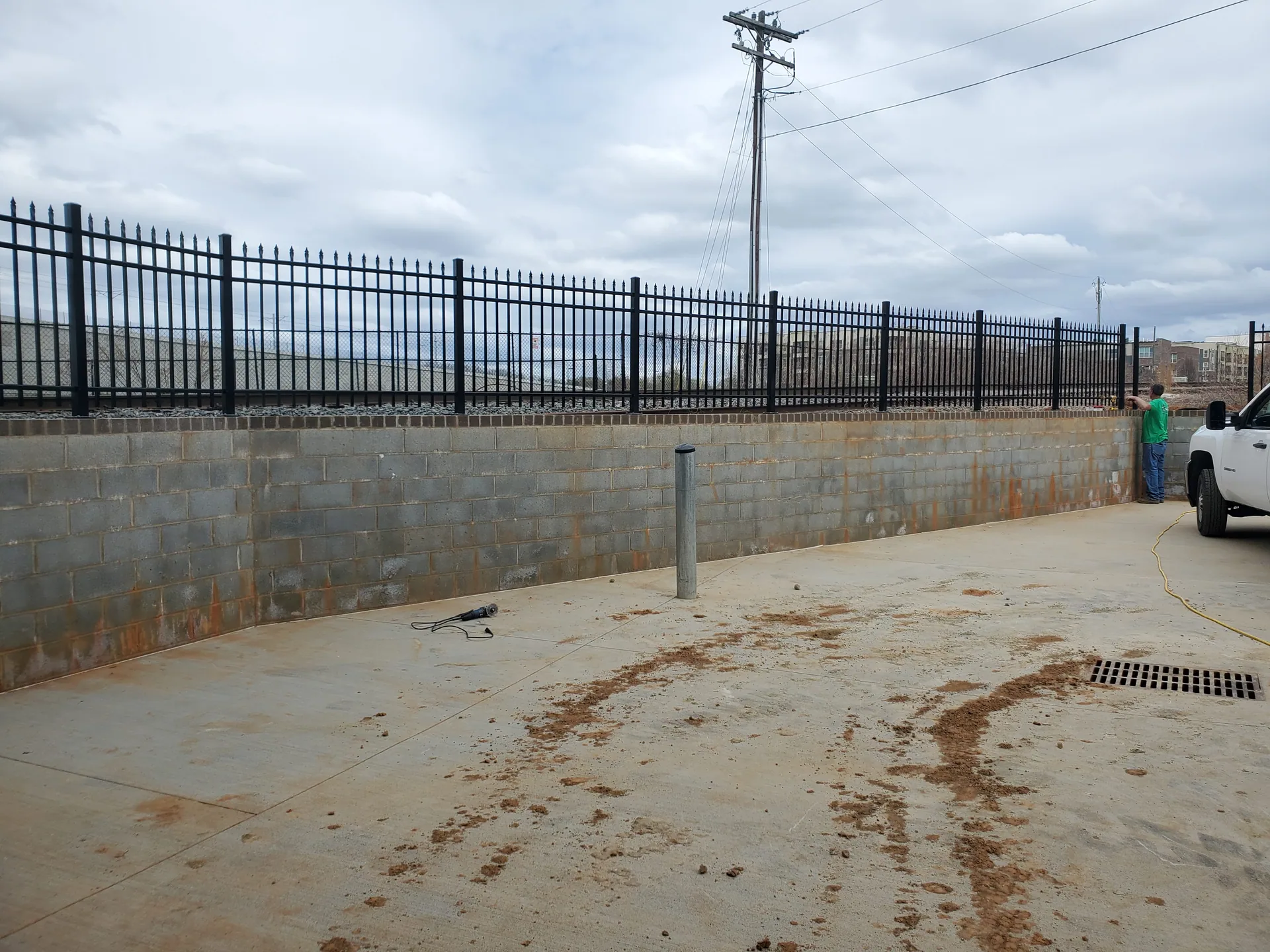 Black aluminum fence atop cinder block retaining wall concrete lot gastonia
