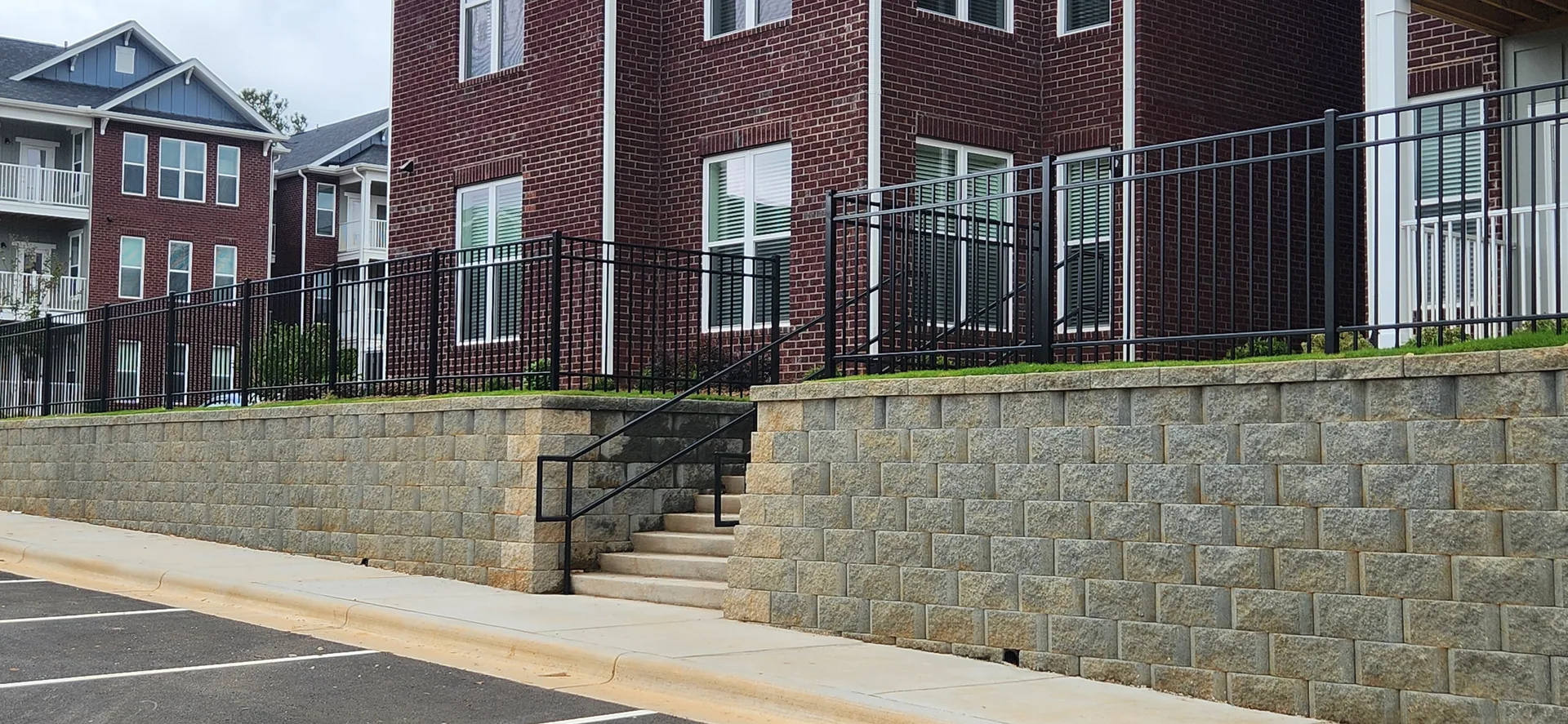 Black aluminum railing segmental block wall concrete steps brick apartments belm