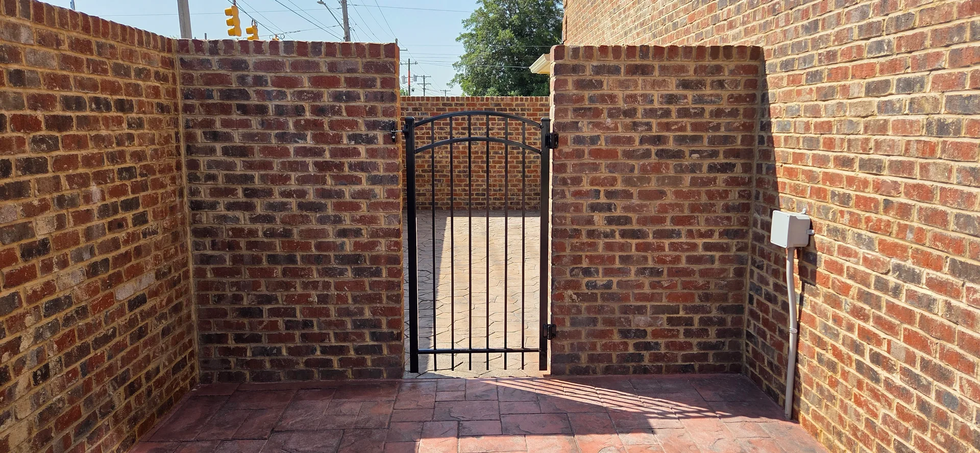 Black arched aluminum walk gate brick walls stamped concrete courtyard gastonia
