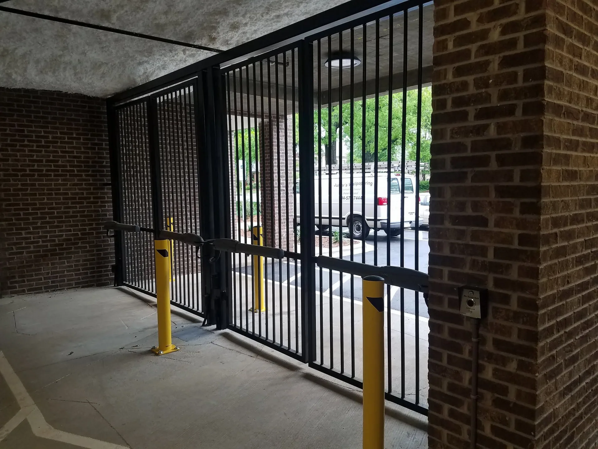 Black steel gate enclosure yellow bollards brick covered entry gastonia