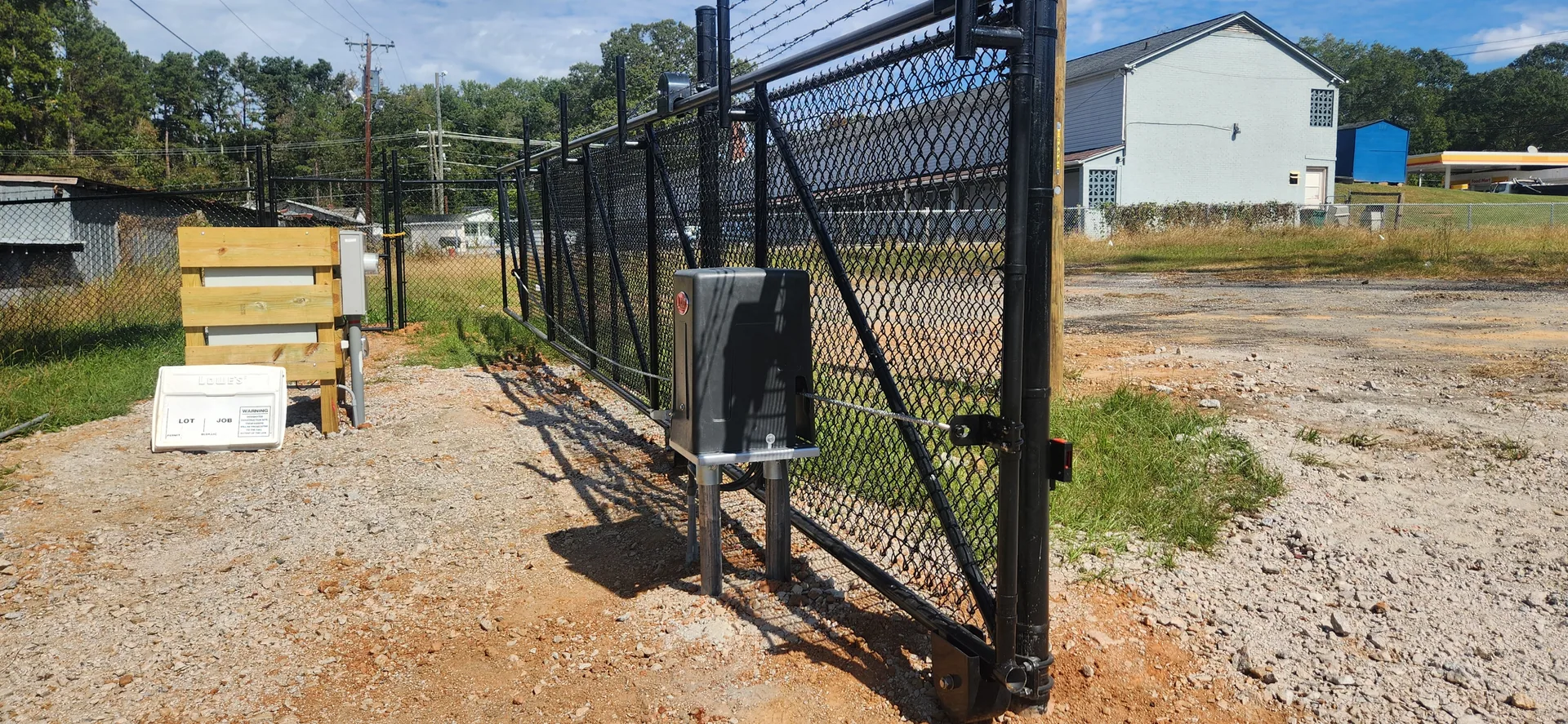 Black vinyl coated chain link slide gate operator barbed wire gravel lot gaston
