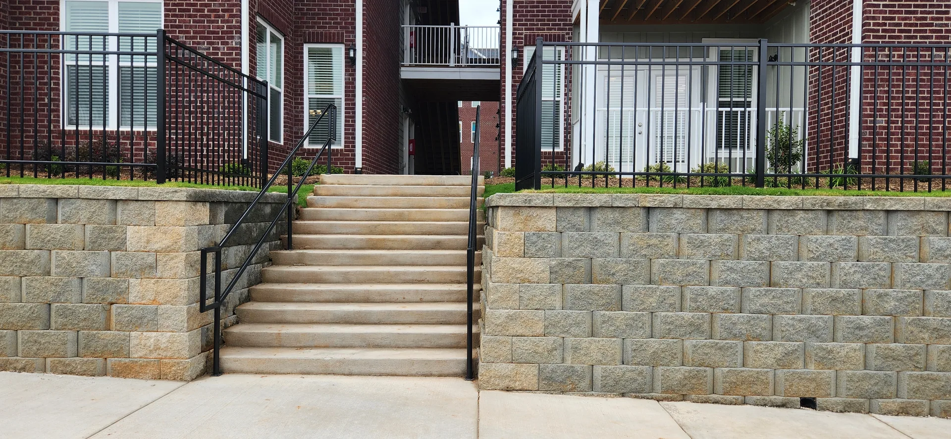 Concrete steps black metal handrails segmental wall fence brick apartments dalla