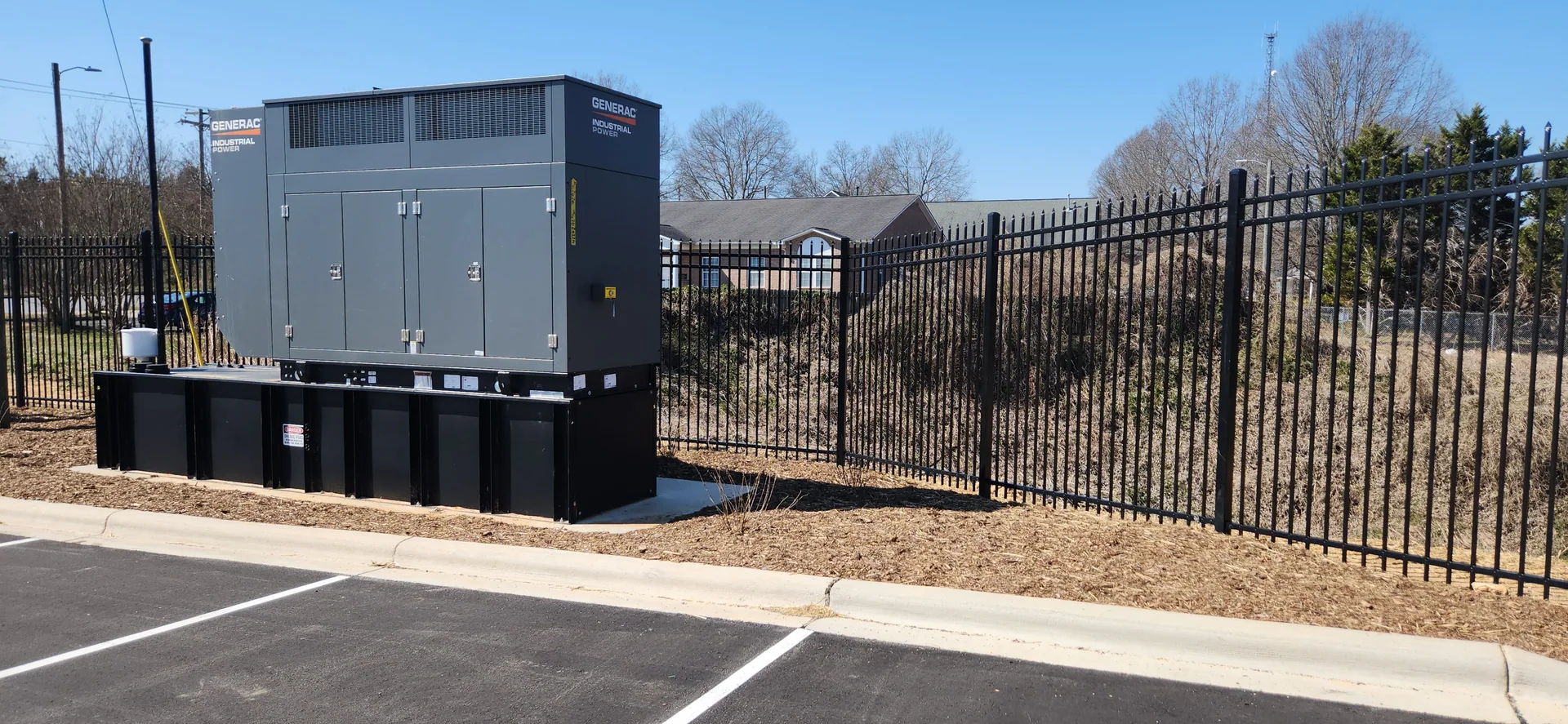Generac industrial generator black aluminum fence parking lot mulch belmont