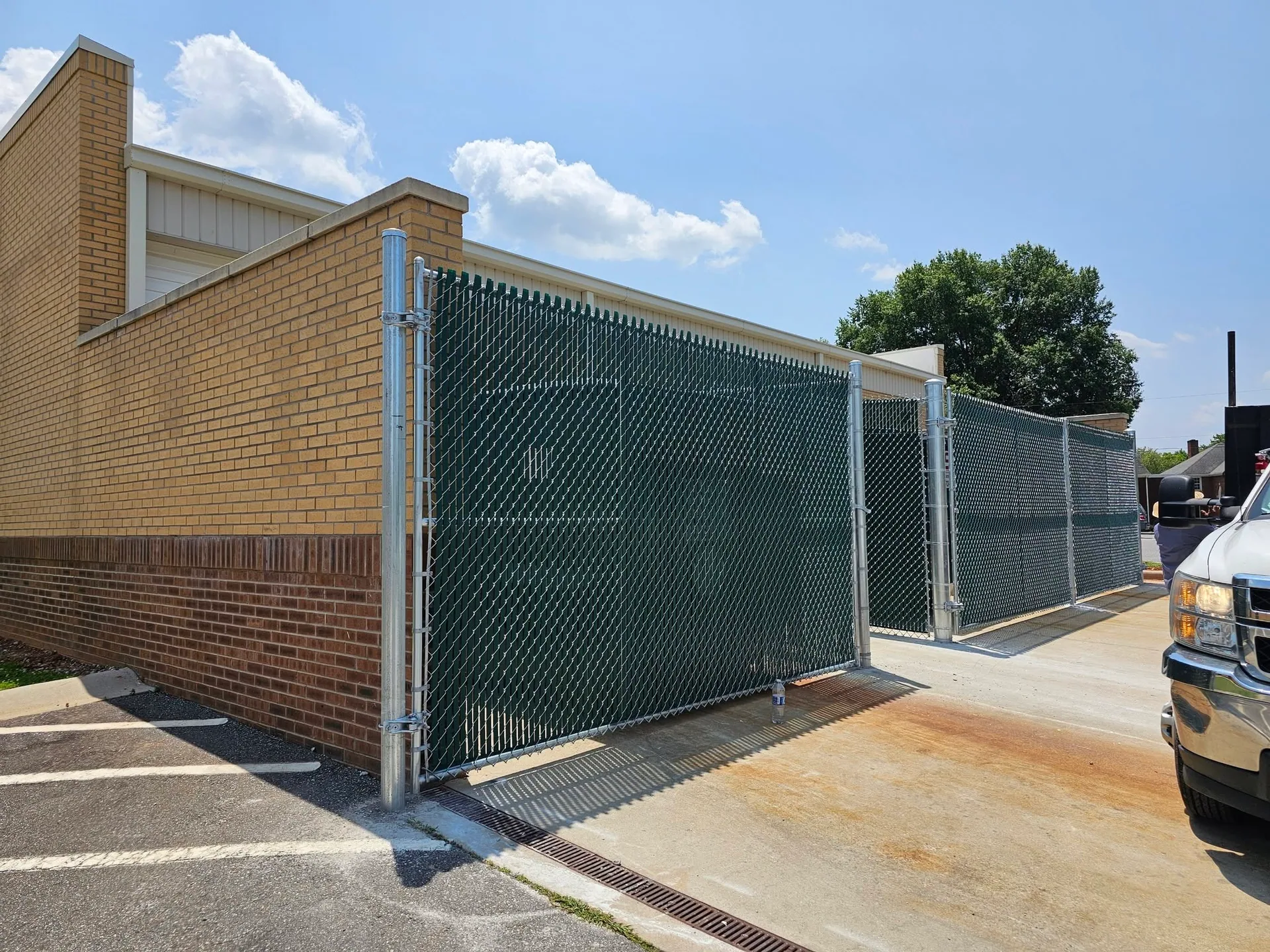 Green slatted chain link gate enclosure brick building parking lot gaston county