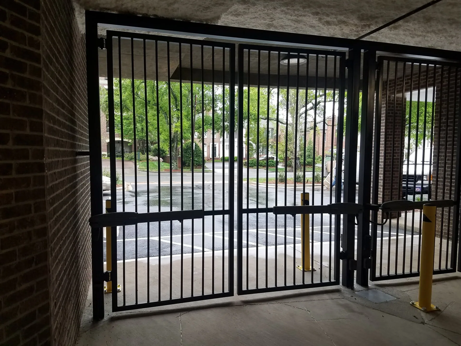 Interior view black steel bar security gates parking breezeway yellow bollards g