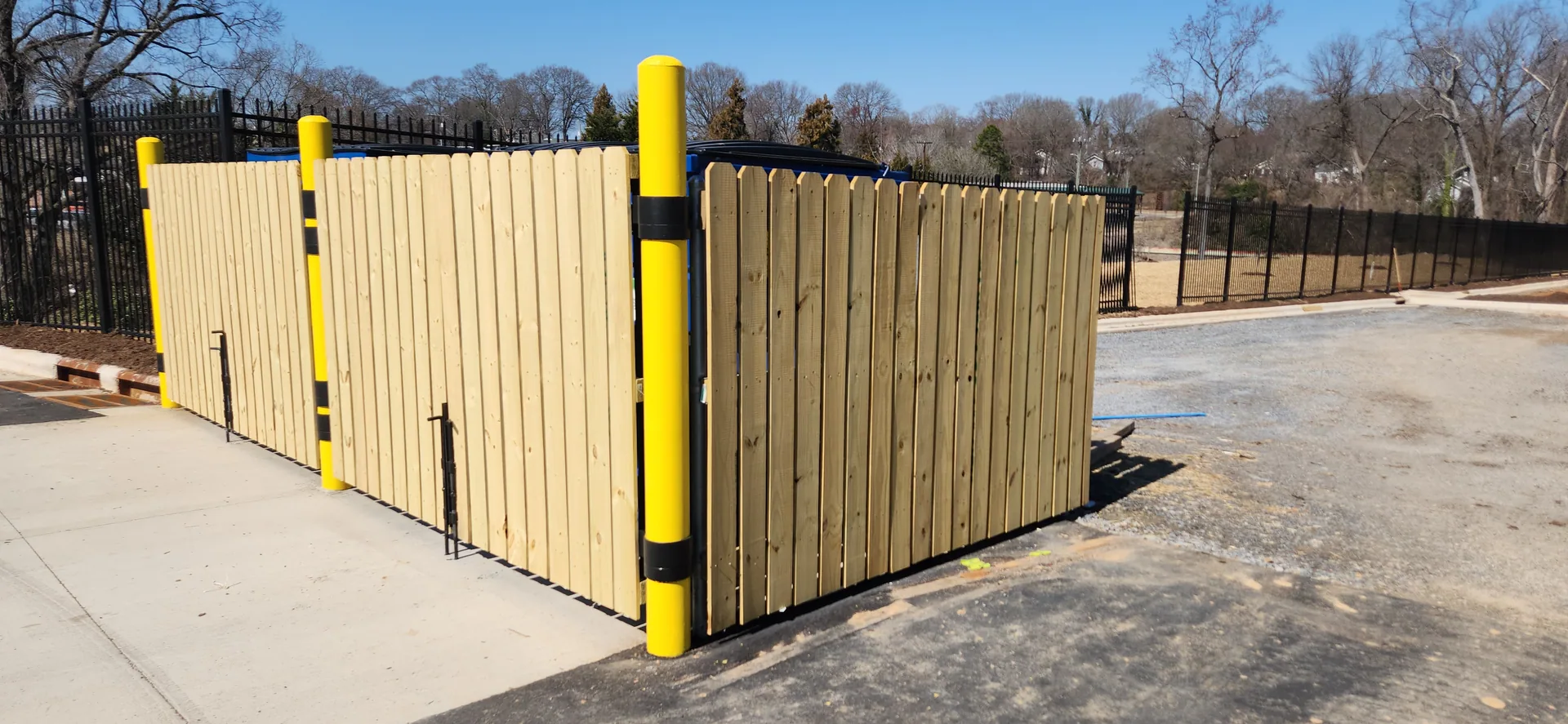 New wood privacy dumpster corral yellow posts black iron fence belmont nc