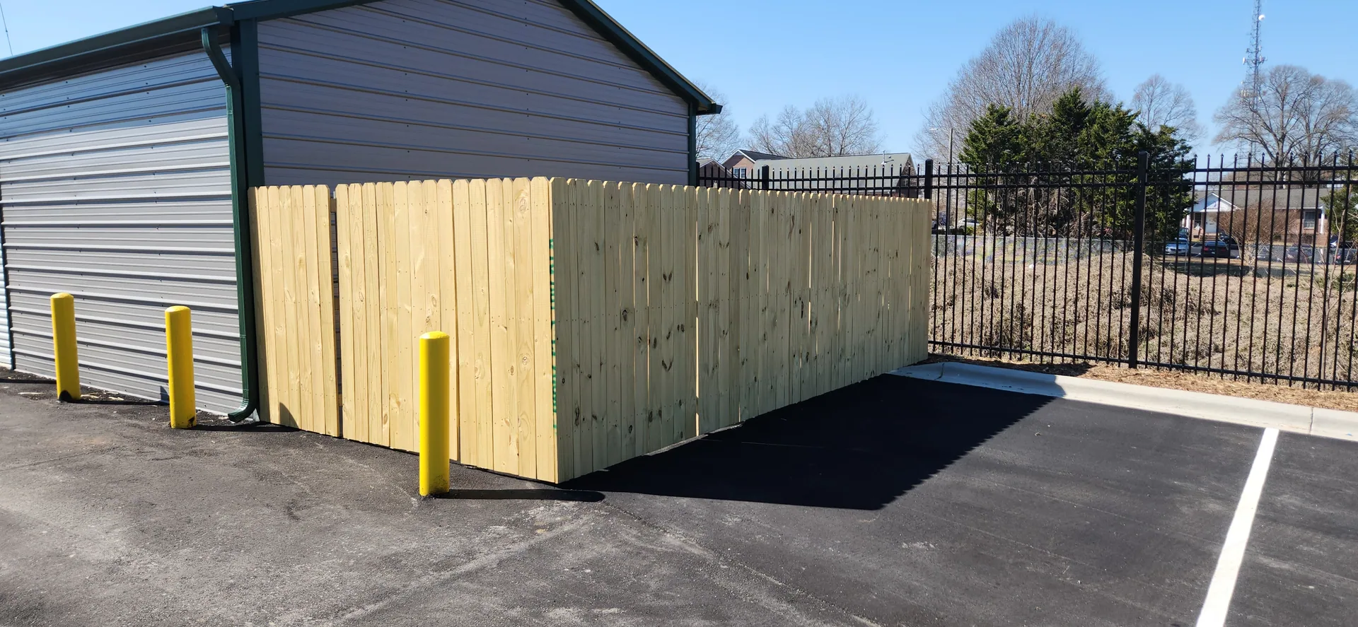 New wood privacy fence enclosure corner metal building asphalt lot gastonia