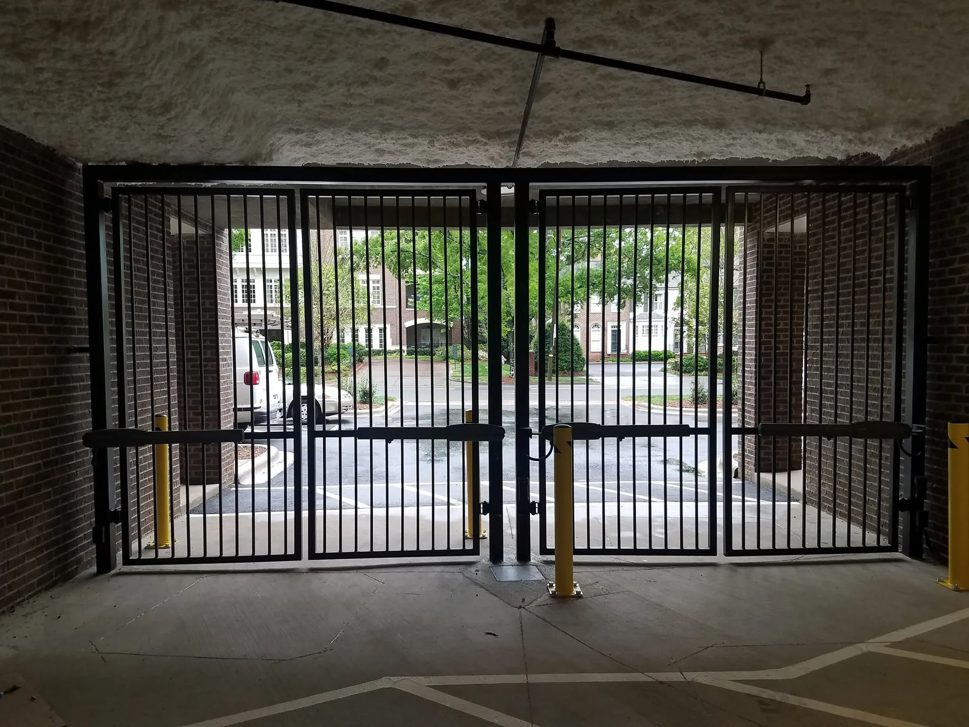 Parking garage entrance black steel gate yellow bollards gastonia access gates