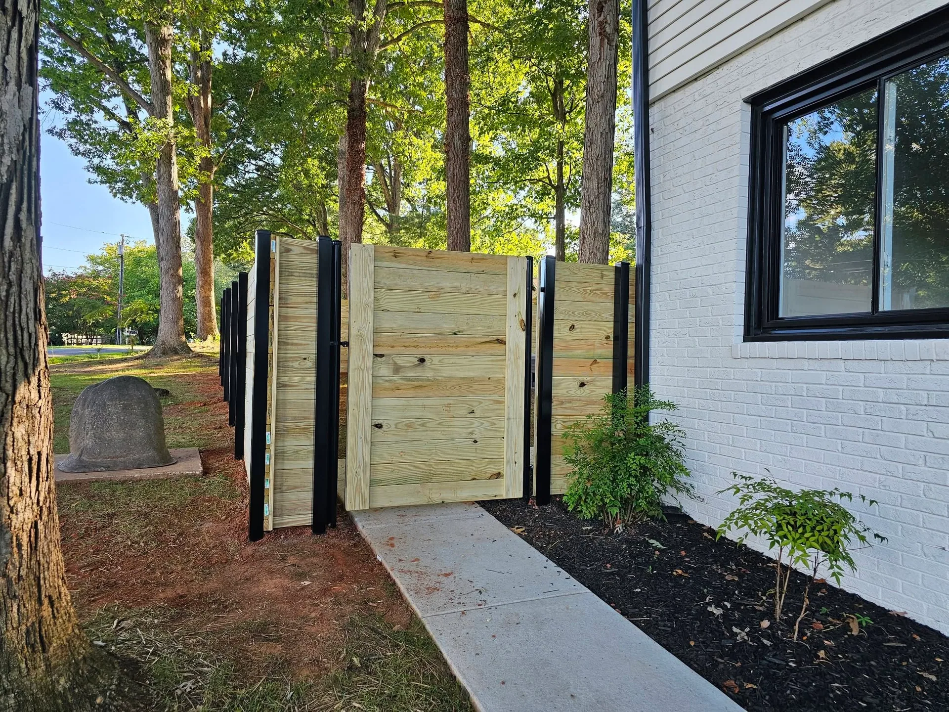 Pressure treated horizontal wood screen enclosure black posts white brick walkwa