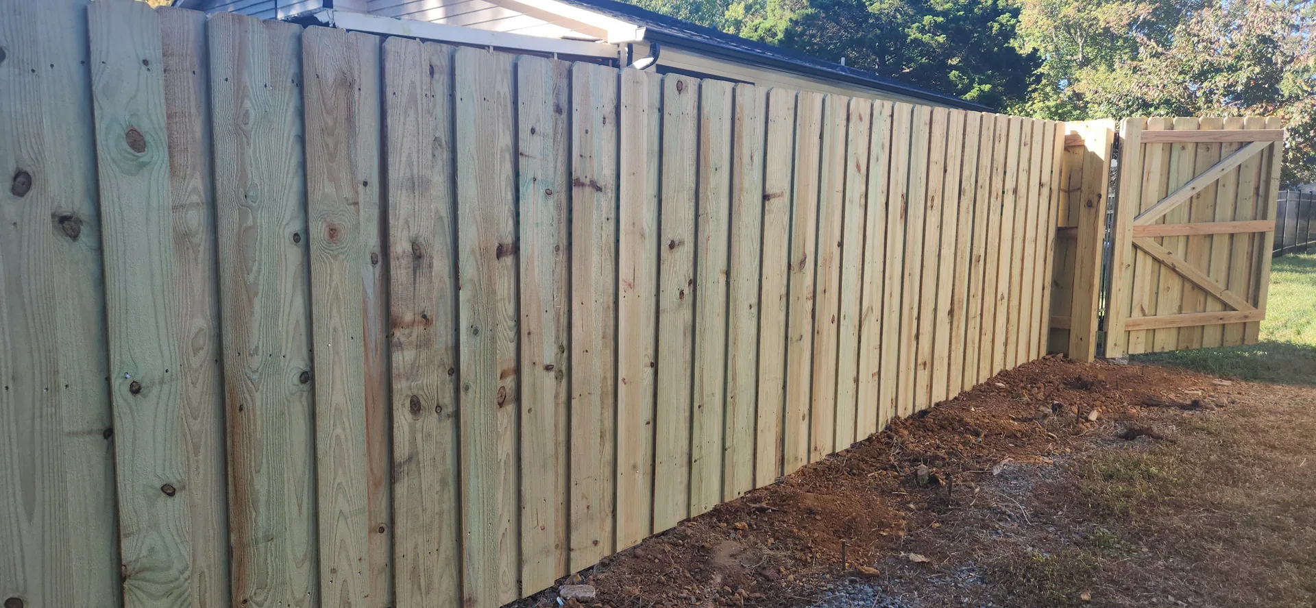 Pressure treated shadowbox wood fence diagonal brace gate bare soil gastonia