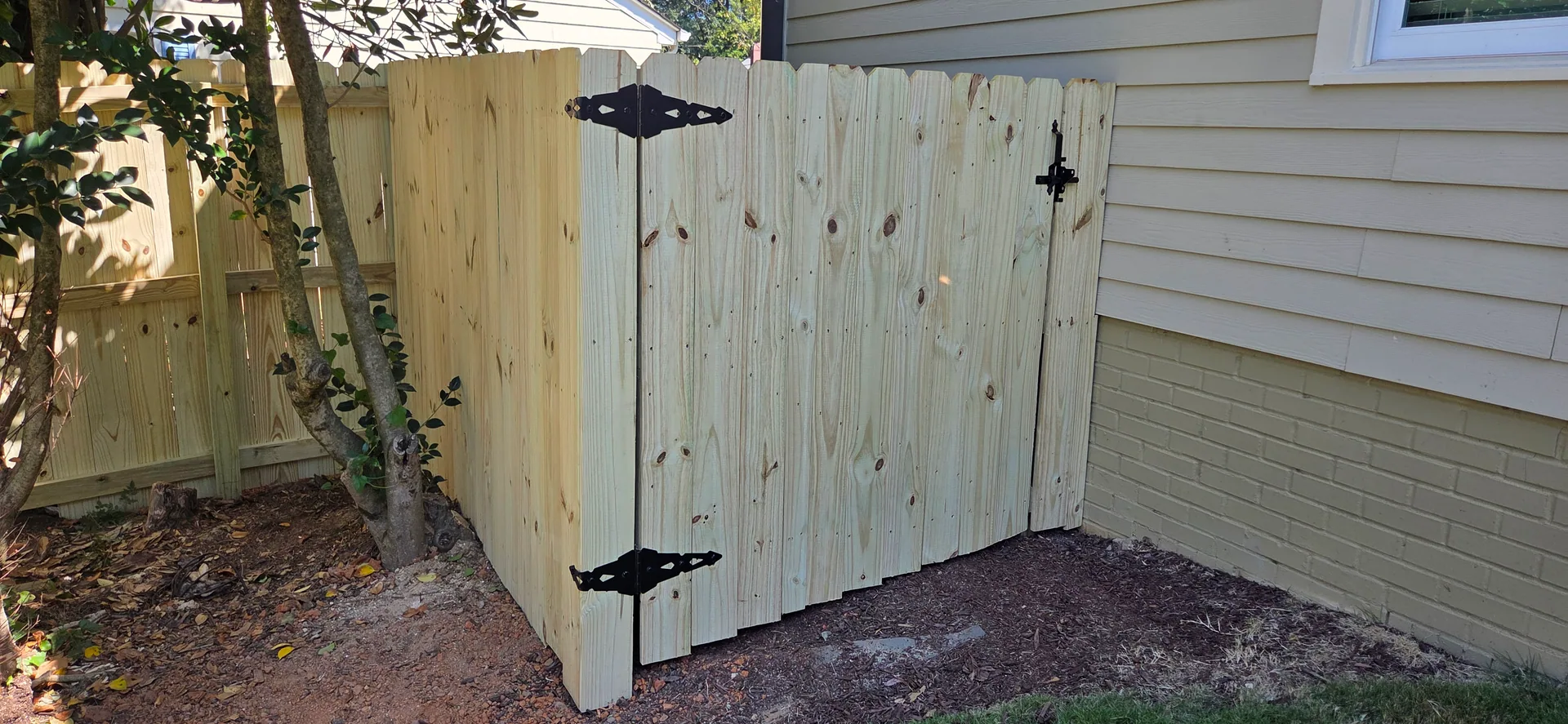 Pressure treated wood gate black strap hinges side yard tan siding lowell nc
