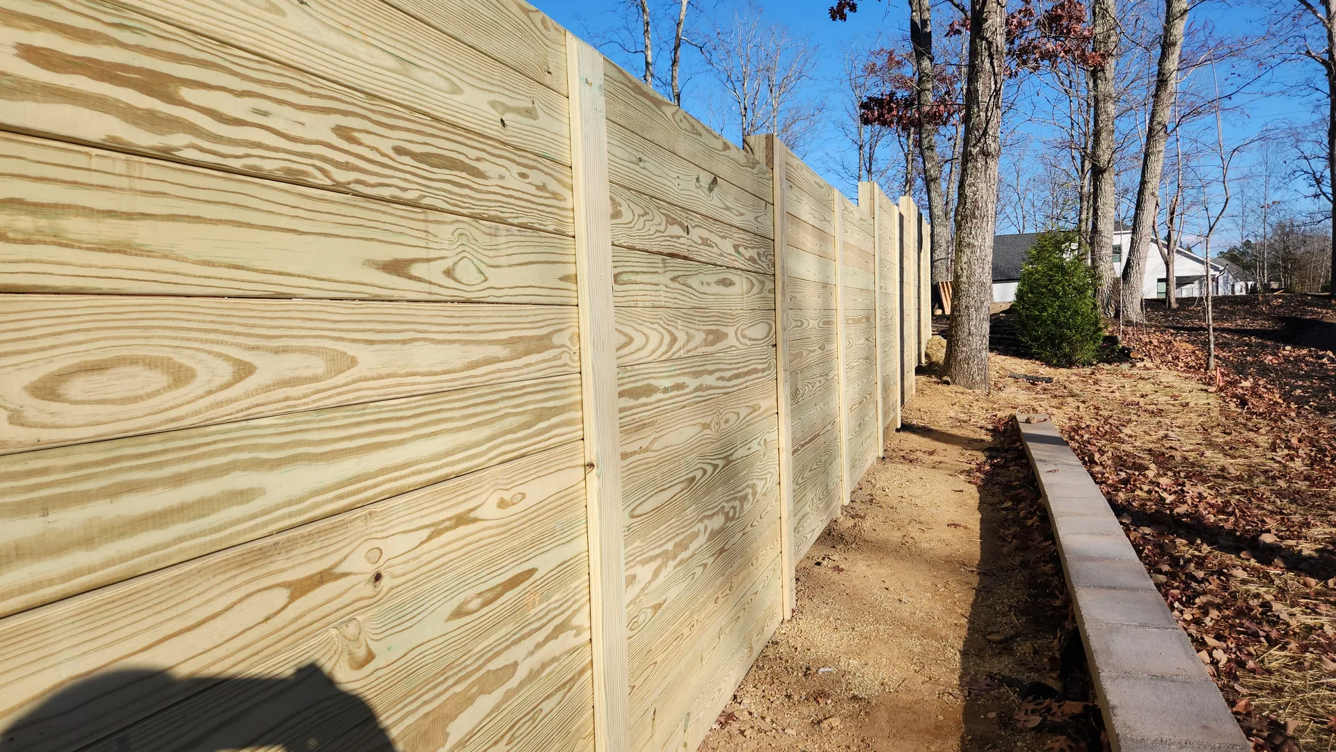 Receding horizontal pine board fence retaining wall bare path bessemer city