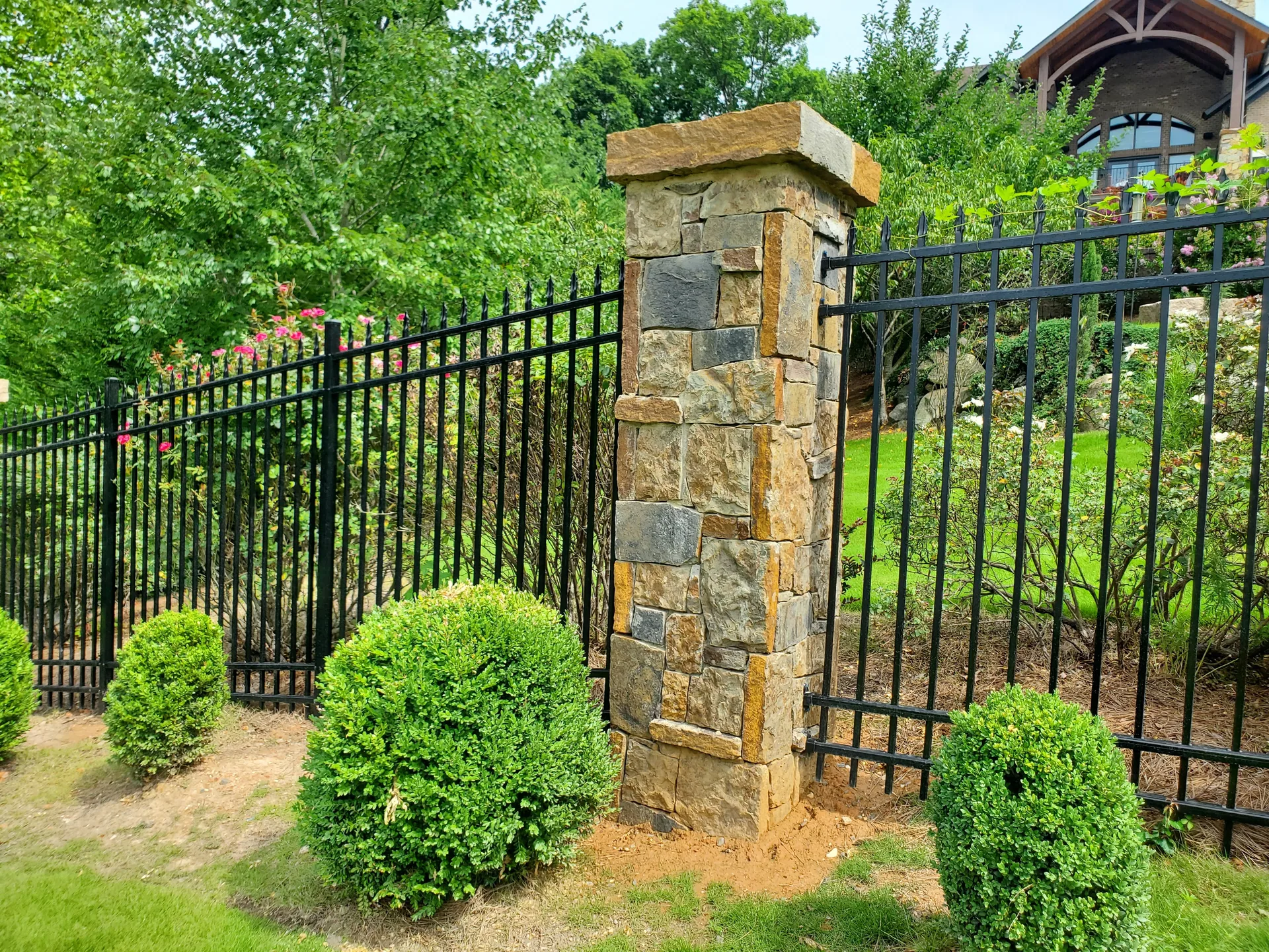 Stone pillar black aluminum fence boxwood shrubs landscaped yard gaston county
