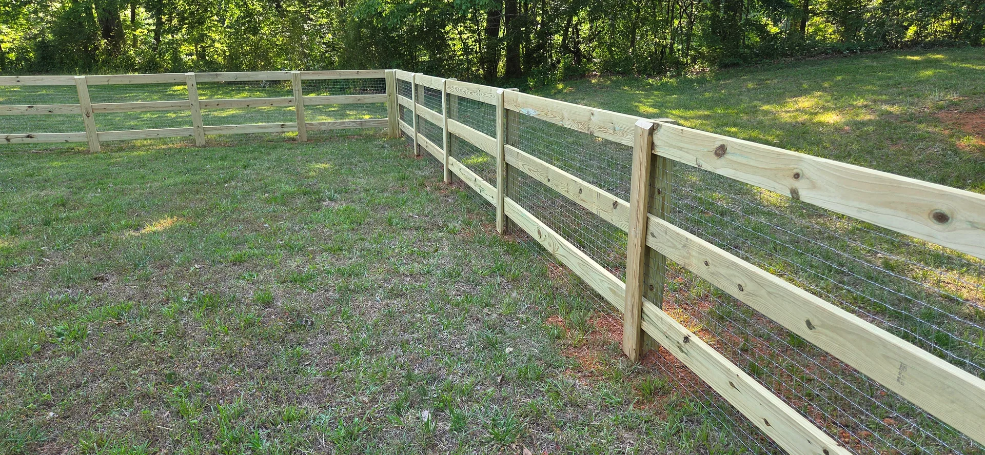 Three rail pressure treated fence welded wire grassy yard corner dallas nc