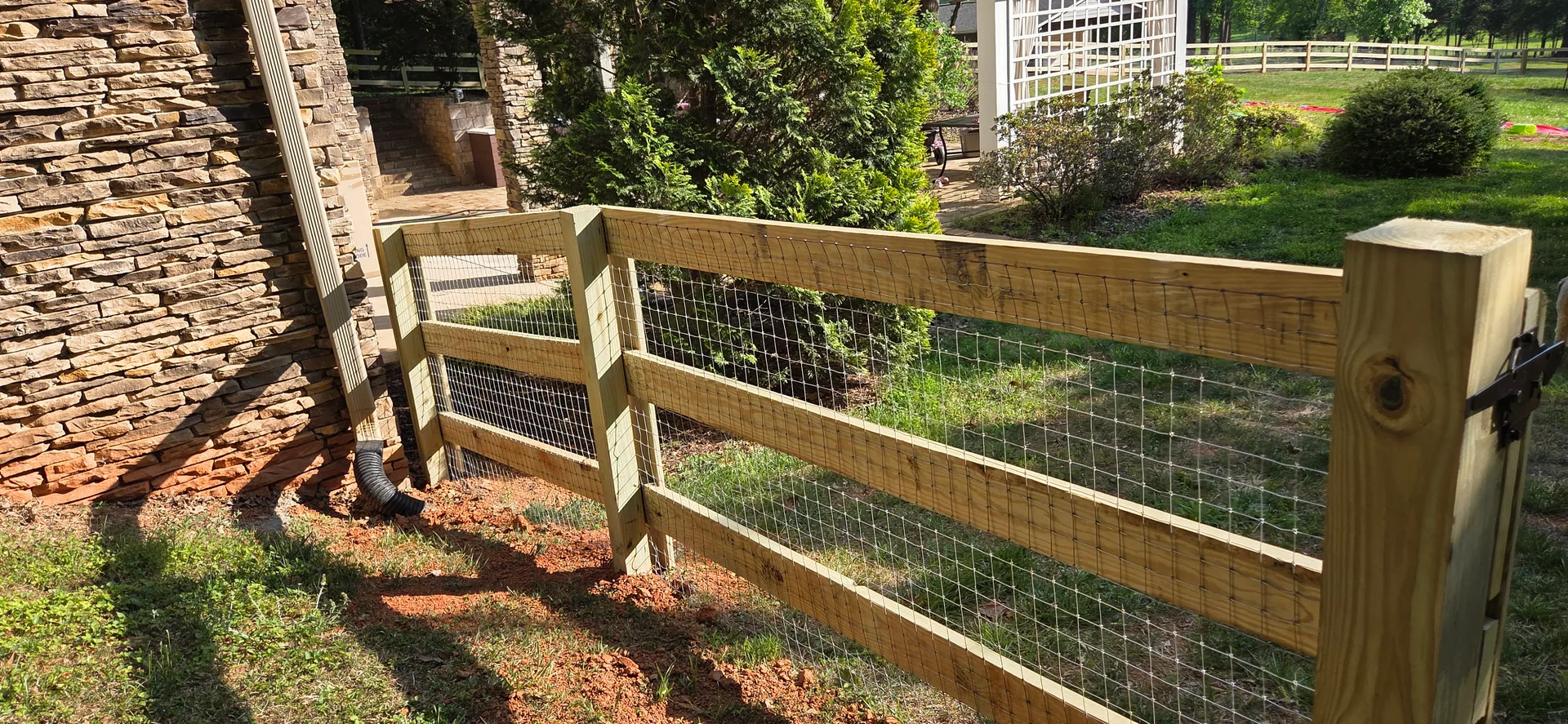 Three rail wood fence wire mesh stacked stone wall gate post gastonia nc
