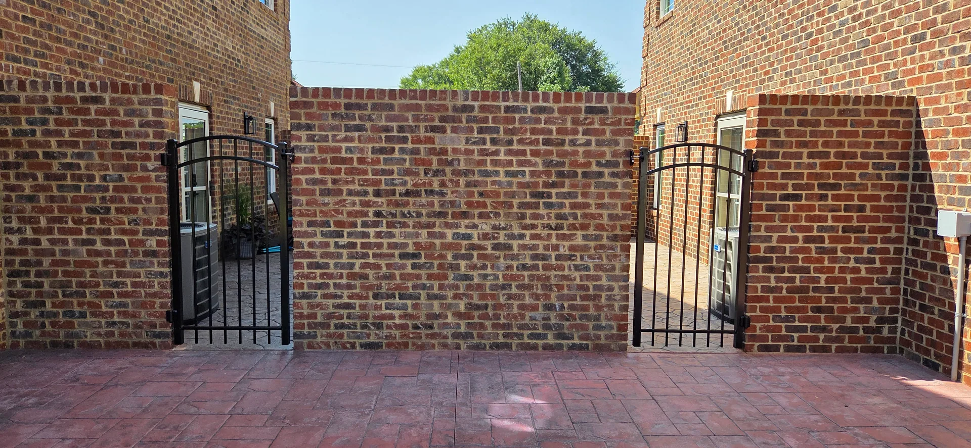 Twin black aluminum arched walk gates brick wall stamped patio gastonia