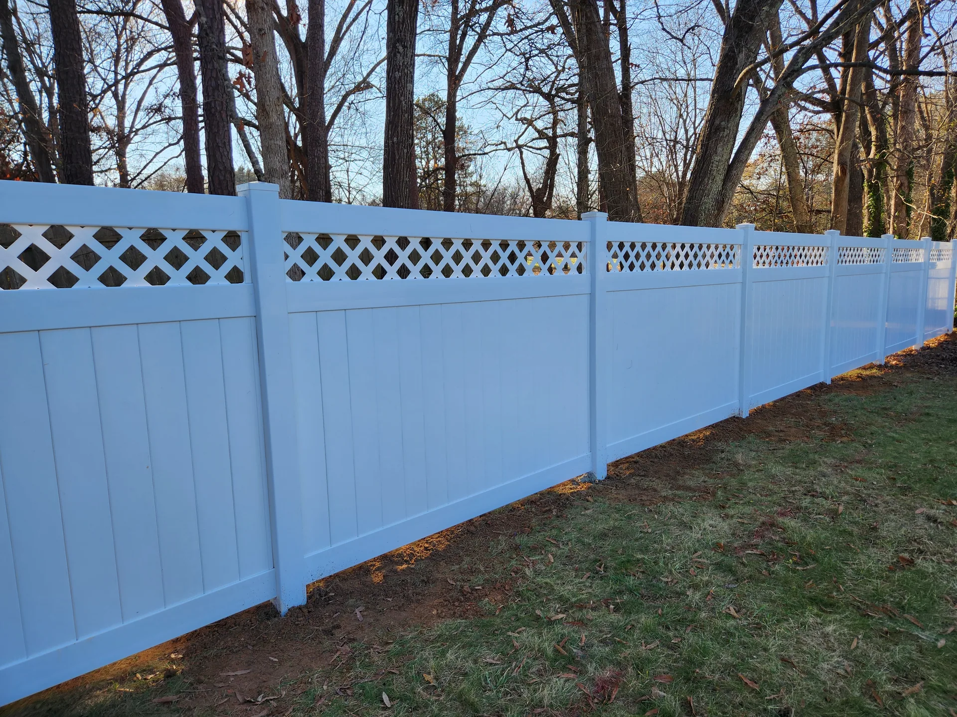 White vinyl lattice top privacy fence bare trees lawn gaston county