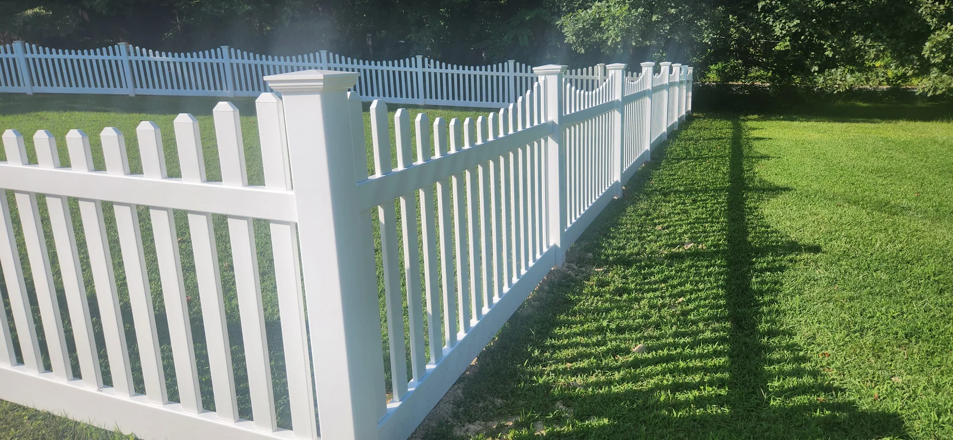 White vinyl picket fence corner post long shadows green lawn gastonia