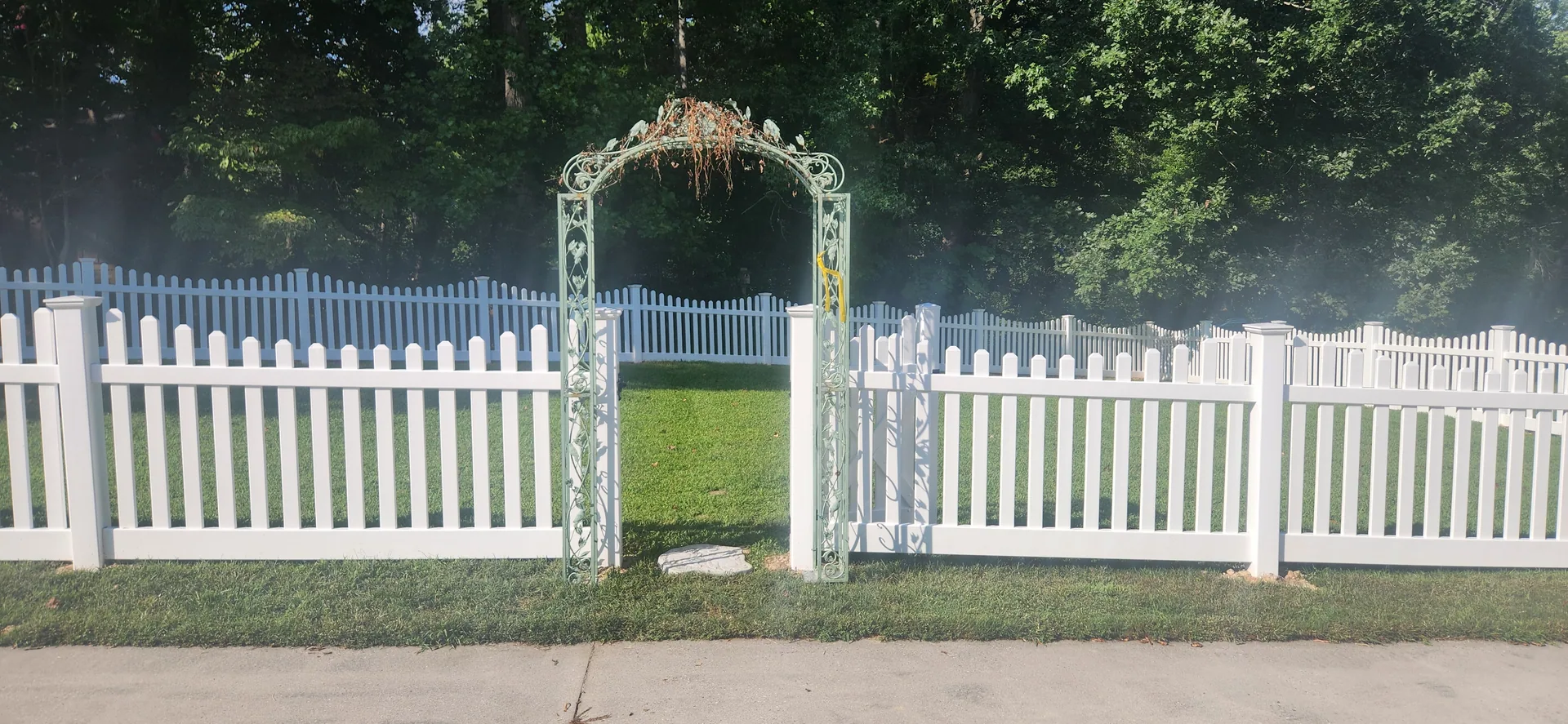 White vinyl picket fence green garden arch opening sidewalk mount holly nc