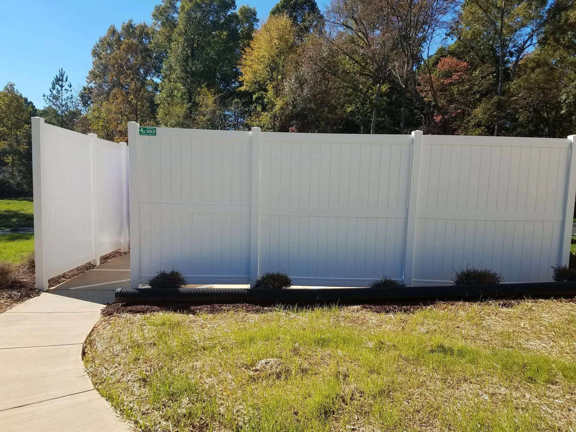 White vinyl privacy fence screen offset panels concrete walkway mulch bed gaston