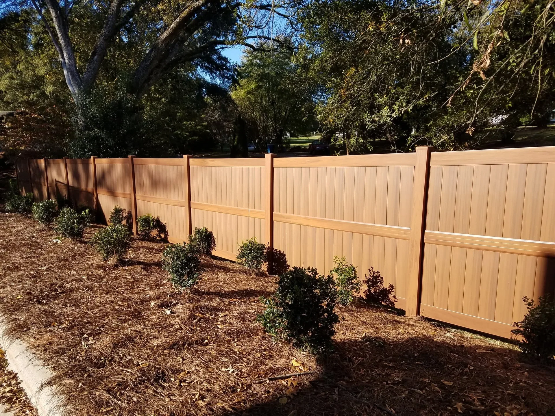 Woodgrain vinyl privacy fence pine straw shrubs curb gastonia nc